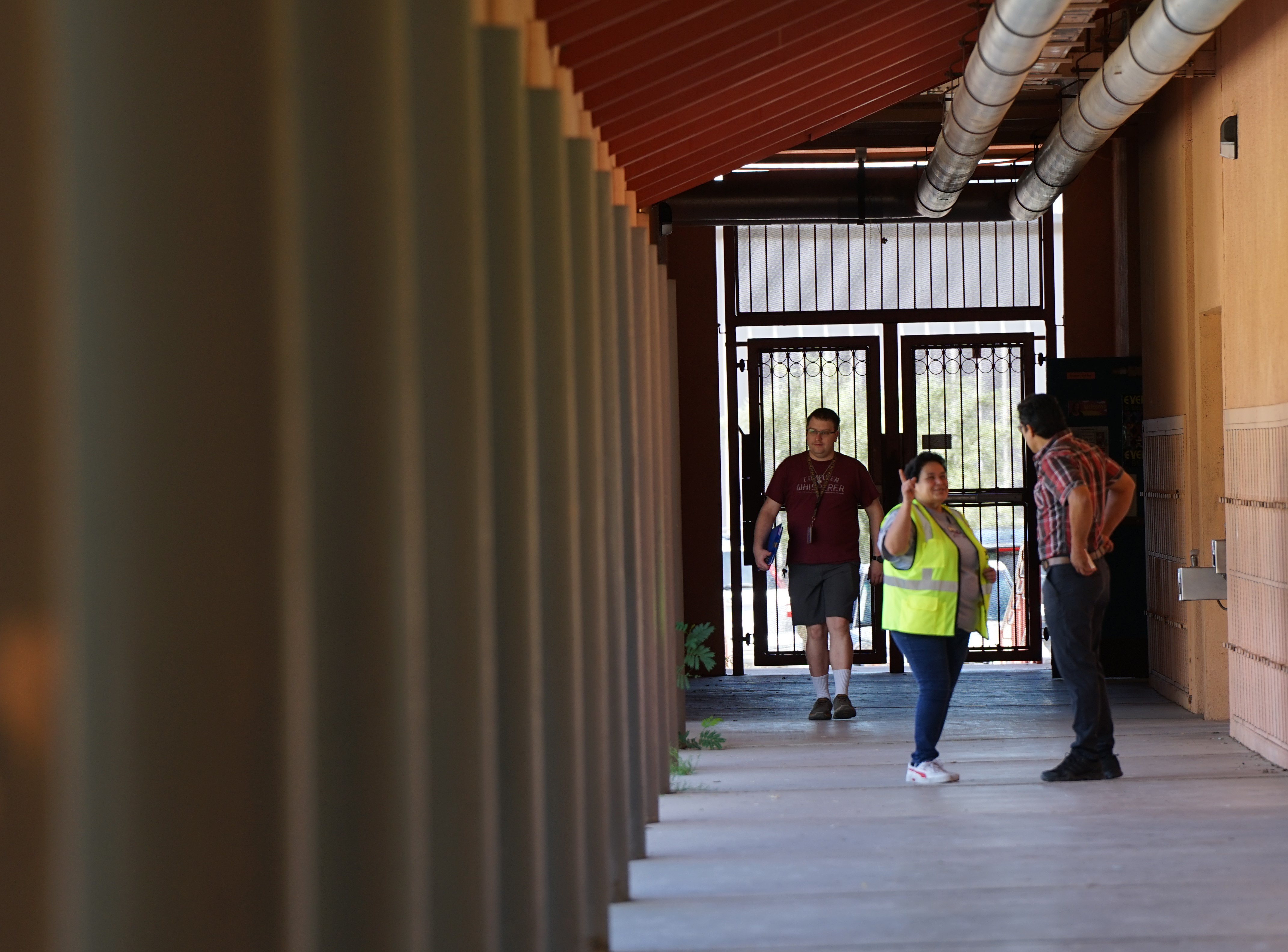 A monitor in a yellow vest talks to a parent in the outside hallway