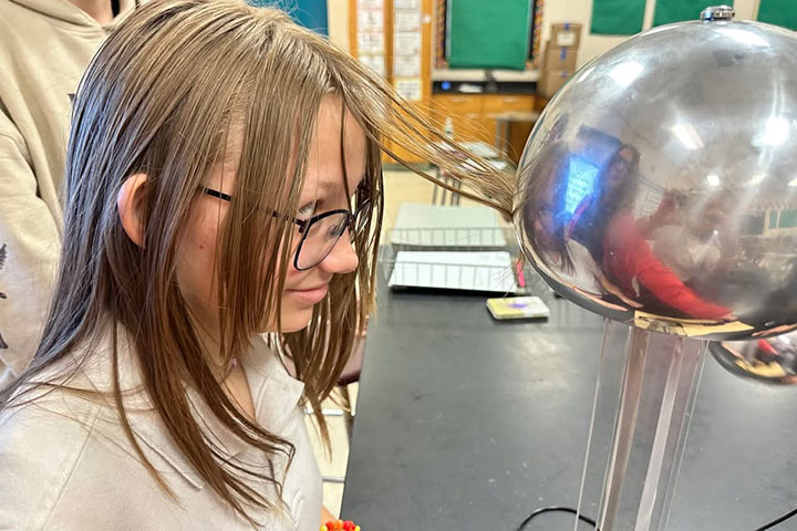 A girl has her hair stuck to a metal ball