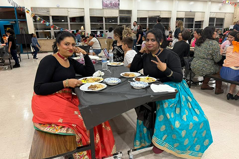 Two women sit at a table enjoying their food
