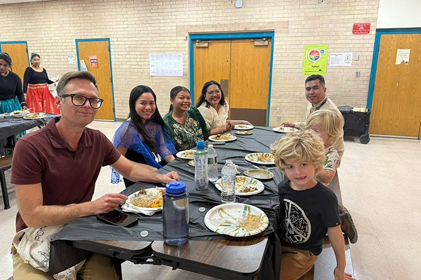 Families sit at a cafeteria table enjoying their food
