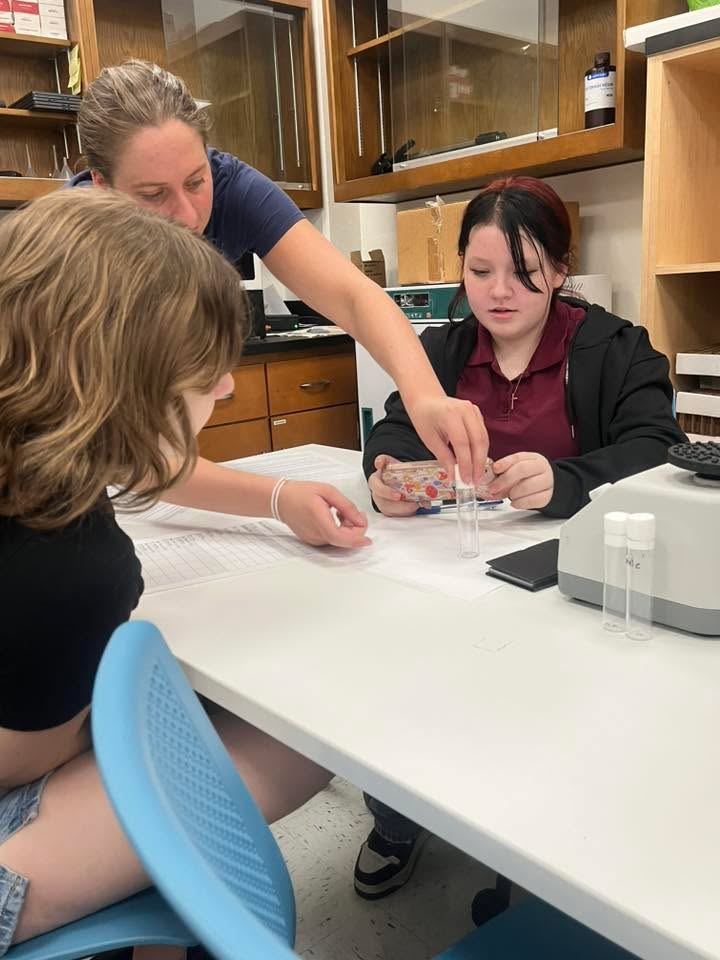 A PhD student works with Doolen students in the lab