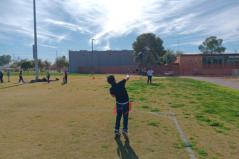 A boy throws a football to his friend across the field