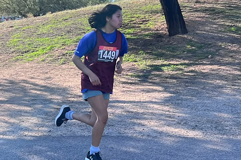 A teen boy runs around a dirt track