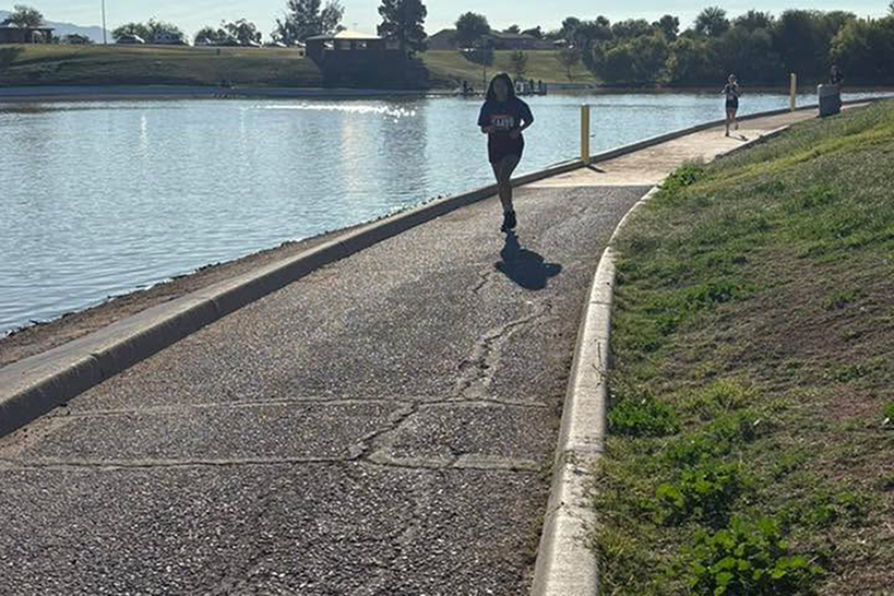 A girl runs on a path around a pond