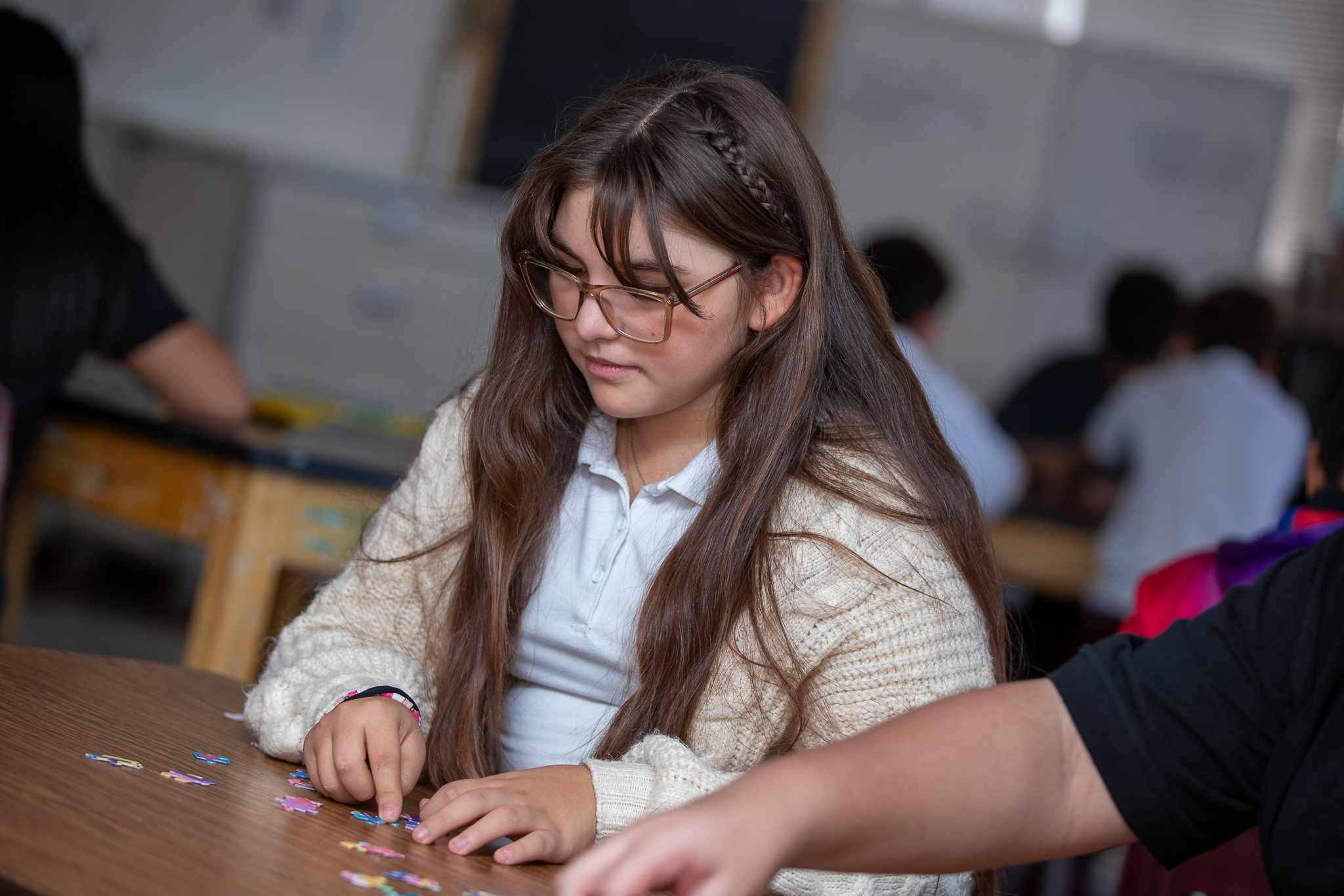 A teen girl focuses as she works on a jigsaw puzzle